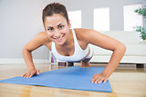 Portrait of fit woman practicing press ups in her living room
