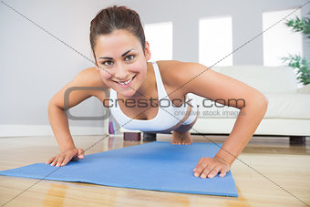 Portrait of fit woman practicing press ups in her living room