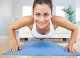 Fit young woman practicing press ups on a blue exercise mat