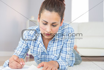 Young brunette student lying on the floor doing assignments