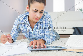 Concentrated pretty student using her tablet for assignments