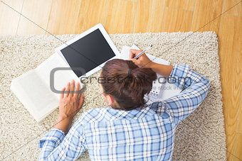 Brunette female student lying on the floor doing assignments