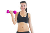 Joyful active woman training with a dumbbell smiling at camera