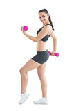 Side view of smiling active woman training with dumbbells