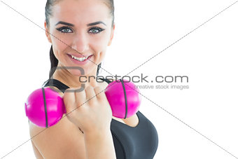 Sporty attractive woman smiling at camera while training with a pink dumbbell