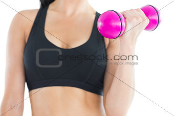 Close up of sporty young woman training with a pink dumbbell