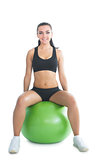 Front view of cute sporty woman sitting on an exercise ball