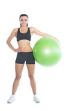 Attractive slender woman posing holding a green exercise ball