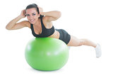 Happy fit woman doing an exercise on a green fitnessball