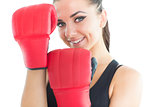 Attractive sporty woman smiling at camera wearing boxing gloves