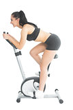 Profile view of sporty young woman training on an exercise bike