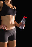 Mid section of attractive slim woman in sportswear holding a water bottle