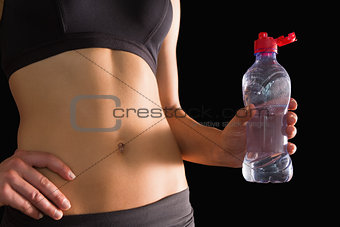 Close up of slim woman in sportswear holding a water bottle