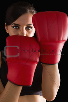 Front view of young sporty woman posing wearing boxing gloves