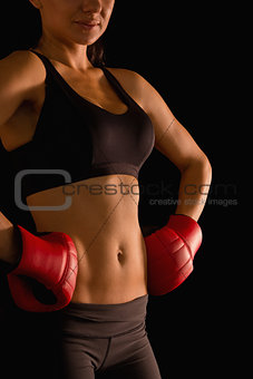 Mid section of young sporty woman posing and wearing boxing gloves