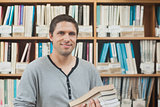 Attractive mature student standing in a library holding some books