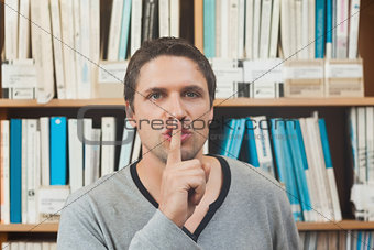 Brunette male librarian requesting silence in library