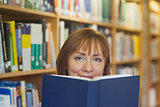 Peaceful mature woman holding a book in a library