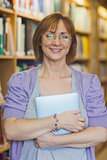 Mature female librarian posing in library holding a tablet