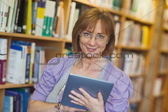 Calm mature librarian working with her tablet in library