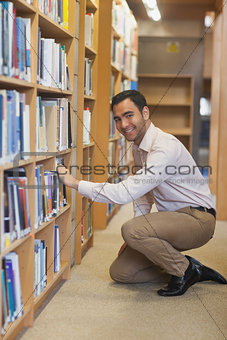Young attractive man cowering in front of bookshelves