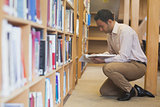 Attractive casual man reading a book in library
