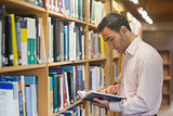 Intellectual man reading a book standing in library