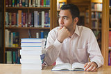 Attractive man sitting in library in front of an opened book
