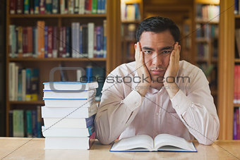 Handsome man sitting in front of an opened book in library