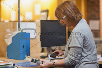 Profile view of mature librarian scanning a book