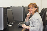 Cheerful female mature student sitting in computer class