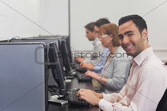 Cheerful mature student sitting in computer class