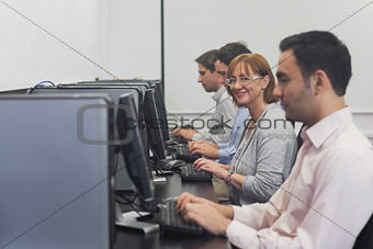 Happy female mature student sitting in computer class
