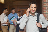 Cheerful attractive mature student phoning in corridor