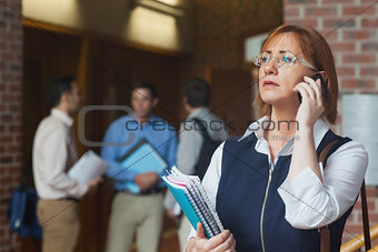 Female mature student phoning standing in corridor