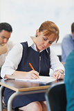 Concentrated female mature student sitting in classroom