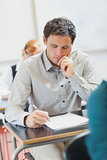 Focused handsome mature student sitting in classroom with classmates
