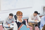 Female teacher posing in her classroom holding some files