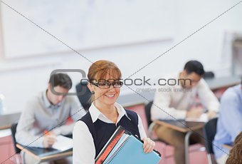 Female teacher posing in her classroom holding some files