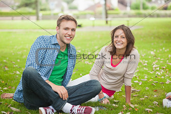 Casual smiling students sitting on the grass
