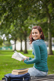 Happy casual student sitting on bench reading