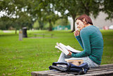Thoughtful casual student sitting on bench reading