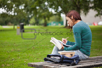Serious casual student sitting on bench taking notes