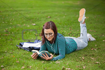 Content casual student lying on grass reading