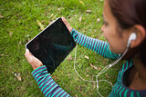 Casual student lying on grass holding tablet