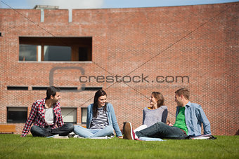 Four casual students sitting on the grass chatting