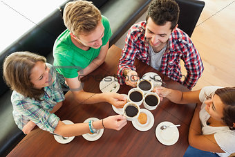 Four happy students having a cup of coffee chatting