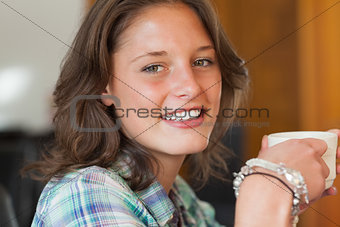 Pretty smiling student having a cup of coffee