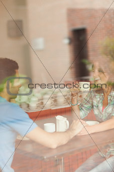 A couple holding hands and drinking coffee