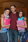 Three cheerful students posing in hallway